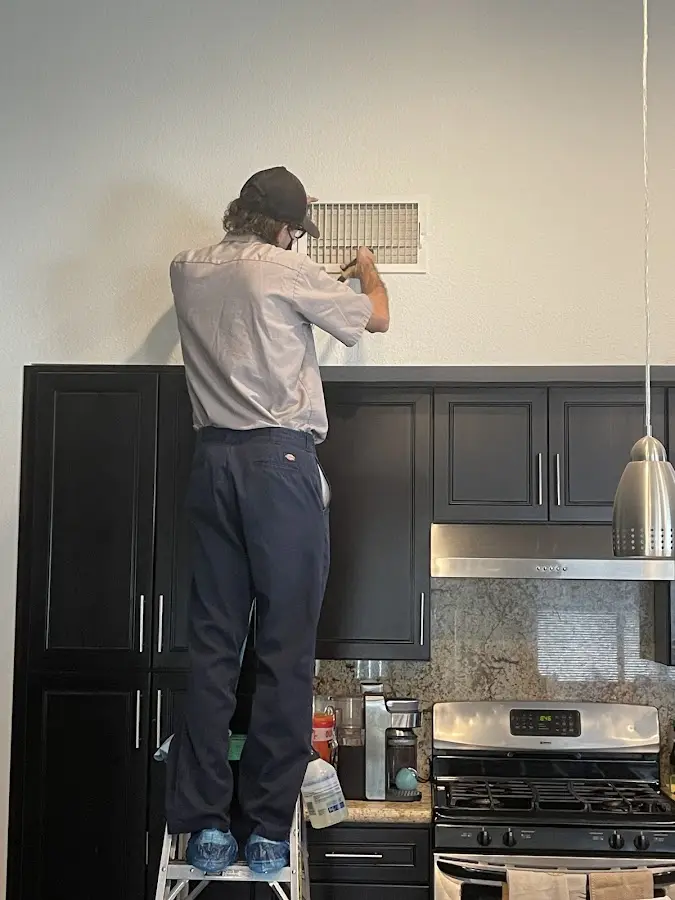 Technician inspecting an air vent during HVAC service in Weslaco